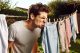 Una persona oliendo la ropa en el tendedero porque no sabe cómo quitar el olor a humedad de la ropa.